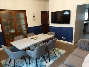 Zimmer mit einem Tisch und Stühlen sowie einem Flachbild-TV in der Unterkunft Villa Napoleon in Les Lilas