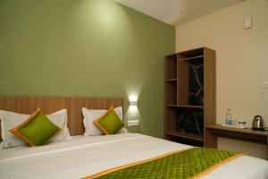 a bedroom with a bed with green and white pillows at Elegant Residency in Coimbatore +22 photos