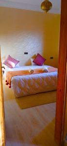 a bedroom with two beds with pink pillows at Dar Amrad in Hassilabied