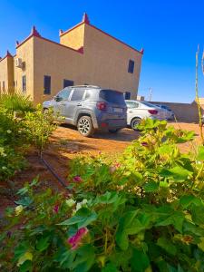 two cars parked in a parking lot in front of a building at Dar Amrad in Hassilabied