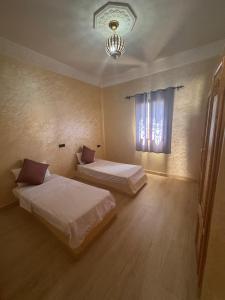 a bedroom with two beds and a chandelier at Dar Amrad in Hassilabied