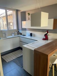 a kitchen with white cabinets and a counter top at Le Rive & Chêne Apartment in Aurillac +2 photos