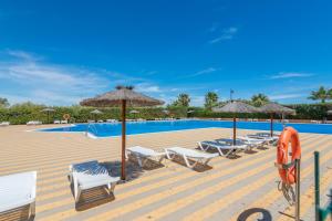 een zwembad met stoelen en parasols en een groep bij Los Albatros by Ĥ - Playa de los Haraganes HAHB30P190 in Isla Canela