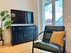 a black chair with a television on top of a cabinet at Renaissance Boutique Apartment - Bad Krozingen in Bad Krozingen