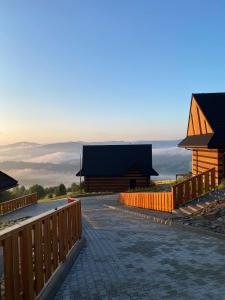 a view of a building with a fence and mountains at Montini - domki z jacuzzi Koniaków in Koniaków