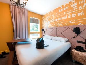 a bedroom with a bed with a bag sitting on it at ibis Styles Carcassonne La Cité in Carcassonne +147 photos