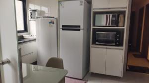 a white refrigerator in a kitchen with a microwave at Lindo apartamento frente mar Peracanga in Guarapari