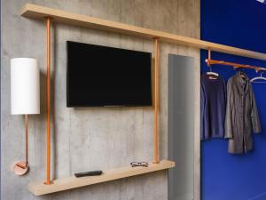 a flat screen tv on a wall with a shelf at ibis budget Amsterdam City South in Amstelveen