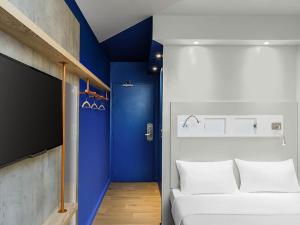 a room with a white bed and a blue wall at ibis budget Amsterdam City South in Amstelveen +88 photos