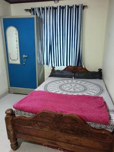 a bedroom with a wooden bed and a blue door at Fortune Holiday cottage in Madikeri
