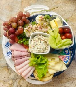 a plate of food with meat and vegetables and grapes at Rezydencja Wind Rose - luxury ApartHotel Gdansk in Gdańsk