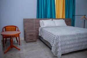 ein Schlafzimmer mit einem Bett, einem Schreibtisch und einem Stuhl in der Unterkunft B First Complex in Kolwezi