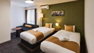 京都&zen Kyoto Gion的一间酒店房间，配有两张床和一张沙发 更多28张照片