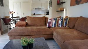a brown couch in a living room with a table at Park Welgelegen, bungalow 67 in Cadzand +12 photos