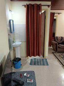 a bathroom with a sink and a red shower curtain at Fortune Holiday cottage in Madikeri +7 photos