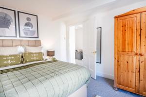 une chambre avec un lit et une armoire en bois dans l'établissement Gloucester Street Nest - 3BR Flat for 6 Guests, à Stroud