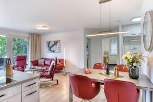 a kitchen and living room with red chairs and a table at Ferienwohnung Meerzeit in der Villa Düne Binz in Binz
