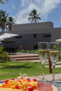 zwei Gläser Weißwein neben einem Teller Essen in der Unterkunft Villa Manatee Rota dos Milagres in Tatuamunha