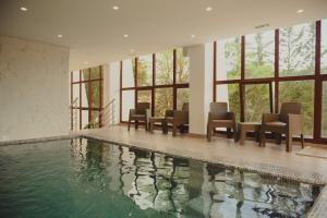 a swimming pool in a building with chairs and windows at Charme Hotel La Foret in Aïn Draham