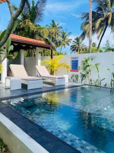a swimming pool with two lounge chairs next to a villa at Villa 2A in Matara