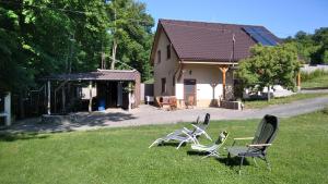two chairs sitting in the grass in front of a house at Chata dobrý pocit in Horné Orešany