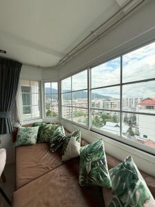 a living room with a couch with pillows and windows at Hillside Condo 2 in Chiang Mai