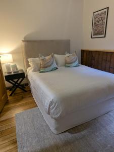 a bedroom with a large white bed with pillows at Quentin's Cottage in Queenstown +37 photos