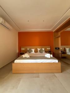 ein Schlafzimmer mit einem großen Bett mit einer orangefarbenen Wand in der Unterkunft Hôtel Everest, Séjour Balnéaire à Saïdia in Saidia  + 12 Fotos