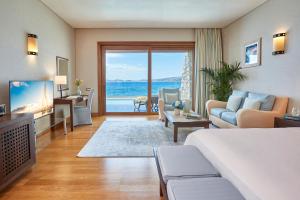 ein Wohnzimmer mit einem Sofa und ein Wohnzimmer mit einem TV in der Unterkunft Grand Resort Lagonissi in Lagonisi