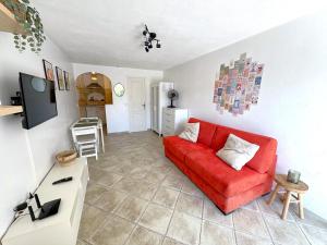 ein Wohnzimmer mit einem roten Sofa und einem Tisch in der Unterkunft Studio cosy à 200m de la plage Parking & Wi-Fi in Bormes-les-Mimosas