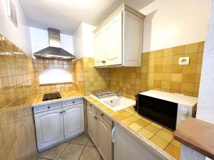 eine kleine Küche mit Spüle und Mikrowelle in der Unterkunft Studio cosy à 200m de la plage Parking & Wi-Fi in Bormes-les-Mimosas + 8 Fotos