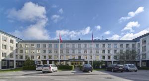 a large white building with cars parked in front of it at Scandic Skärholmen in Stockholm