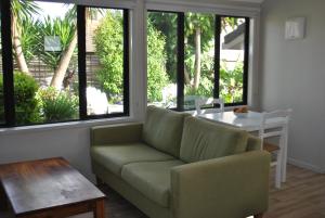sala de estar con sofá, mesa y ventanas en Terry and Cindy's Bed and Breakfast en Auckland