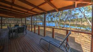 a porch with chairs and a table and a view of a river at Tiny Away Escape at Granite Belt - Sommerville Valley in Stanthorpe