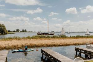 a person in a kayak on a river with boats at Herenhuis geschakeld | 6 personen - Boutique Parc Pharshoeke in Heeg