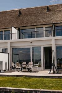 a patio with chairs and a table in front of a building at Herenhuis geschakeld | 6 personen - Boutique Parc Pharshoeke in Heeg