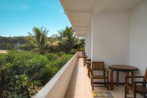 a balcony with tables and chairs and palm trees at New Summer Garden in Unawatuna