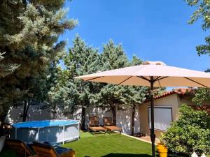 a patio with an umbrella and a hot tub at Daydream Nature Home - Hot Tub & Cinema Experience in Oinóï