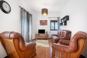 a living room with two leather chairs and a tv at Casinha Da Aldeia in Cela Velha