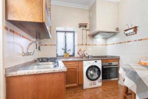 a kitchen with a sink and a washing machine at Casinha Da Aldeia in Cela Velha