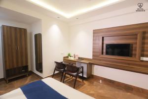a hotel room with a desk and a flat screen tv at Hotel Wedlock in Gurgaon