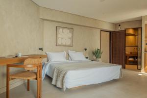 a bedroom with a white bed and a desk and a chair at Beau Rivage Suites in Lóngos
