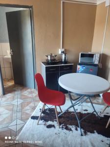 a kitchen with a table and two red chairs and a table at Di-Koena cottage in Springs