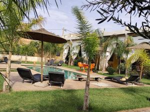 a pool with chairs and a table and an umbrella at Riad Safran Ralya in Marrakesh
