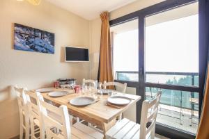 einen Esstisch mit weißen Stühlen und ein großes Fenster in der Unterkunft L'Alpine Classique - Station de Ski à pied in Chamrousse
