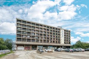 ein großes Gebäude mit auf einem Parkplatz abgestellten Autos in der Unterkunft L'Alpine Classique - Station de Ski à pied in Chamrousse