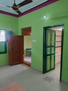 a room with green walls and a door and a room with a table at Arunachala Home Stay - Closest to Temple in Tiruvannāmalai