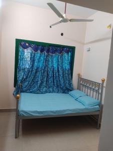 a bed with a blue curtain and a ceiling fan at Arunachala Home Stay - Closest to Temple in Tiruvannāmalai