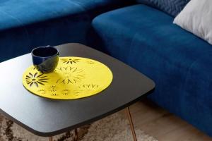 ein gelber Teller auf einem Tisch neben einem blauen Sofa in der Unterkunft Piękny Słoneczny Apartament Blisko Plaży dla 4 Osób by Noclegi Renters in Przymorze + 25 Fotos