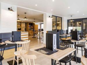 a restaurant with wooden tables and chairs and tablesktop at ibis Styles Rouen Val De Reuil in Val de Reuil